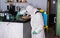 Worker in hazmat suit wearing face mask protection while making disinfection inside bar restaurant - Coronavirus decontamination