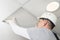 A worker in a helmet installs the last piece of the false ceiling