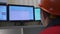 Worker in helmet looks at monitors controlling systems