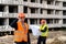 worker holding a helmet with his hand another worker stands further with a work plan