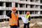 worker holding a helmet with his hand another worker stands further with a work plan