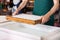 Worker Holding Mold Over Pulpy Water At Paper