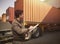 Worker Holds a Clipboard Controlling the Loading of Cargo into Shipping containers. Trucks Parked Loading at Dock Warehouse