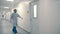 Worker of hospital walk through corridor into one of the rooms