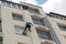 A worker industrial climber on the wall of an apartment building. On a special bench. rope