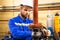 Worker on industrial plant. Technician operator turning gate valve on boiler system. Man in helmet and workwear services refinery