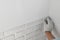 Worker installing decorative wall tiles in room, closeup