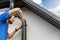 Worker installing house roof gutter