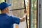 Worker installing mosquito net wire mesh in plastic window frame