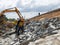 Worker installing riprap slope protection in a road construction project. Road slope protection from landslides.