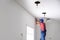 Worker installing stretch ceiling in empty room