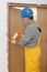 Worker installing wooden door, using polyurethane foam