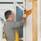 Worker installing wooden door, using polyurethane foam