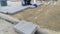 Worker installs large concrete blocks on a sandy surface - 10s