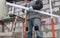 A worker installs a metal profile on the walls of a siding house