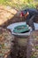 A worker installs a sewer manhole on a septic tank made of concrete rings. Construction of sewage disposal systems for private