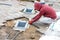 A worker installs utility shafts and lays paving slabs around them