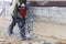 A worker with a jackhammer at a construction site levels a concrete wall. Powerful manual industrial equipment. Difficult