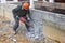 A worker with a jackhammer at a construction site levels a concrete wall. Powerful manual industrial equipment. Difficult