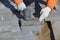 A worker knocks on paving slabs with a construction hammer.