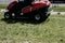 A worker on a lawnmower cuts grass