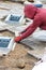 A worker lays paving slabs around utility hatches