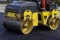 Worker leads the vibrating road roller to compact