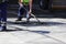 The worker is leveling the crumb of asphalt in the pit with a drag-roller before the paving with a road mini building roller.