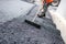 Worker leveling fresh asphalt on a road construction site