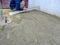 Worker levels dry mortar with an aluminum plate at an outdoor construction site. The process of preparing the site for laying