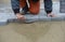 A worker levels the sand near a concrete tile.