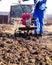 Worker with a machine cultivator digs the soil in the garden