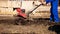 Worker with a machine cultivator digs the soil in the garden