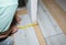 Worker making laminate flooring in apartment. Measure tape and pencil in hands. Maintenance repair renovation. Wooden parquet