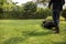 A worker man cutting grass in green yard with electric lawnmower on sunlight