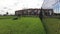 Worker man cutting grass lawn in private townhouse yard on cloudy day. Time-lapse