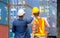 Worker man and Female foreman in hardhat and safety vest control loading containers box from cargo, Teamwork concept