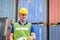 Worker man in hard hat and safety vest standing on container stackers control loading containers box from cargo