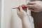 Worker manually tightening an artwork hang screw into a drilled hole in white wall with screwdriver, renovating, decorating and