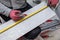 Worker marking ceramic tile with pencil and measuring tape for cutting