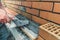 Worker or mason hands laying bricks close up. Bricklayer works at brick row. Brickwork on construction site