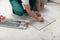 Worker measuring and marking ceramic tile on floor