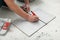 Worker measuring and marking ceramic tile on floor, closeup