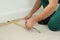 Worker with measuring tape installing carpet indoors, closeup