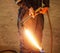 Worker with metal cutting torch in recycle factory