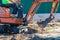 A worker on a minitractor rakes the earth with a bucket. Land works.