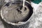 Worker mixing concrete in bucket indoors, closeup