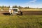 A worker monitoring industrial installation of sod by Bobcat tractor