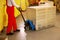 Worker moving wrapped wooden pallets with manual forklift in warehouse, closeup