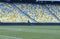 Worker mowing lawn on football field using grass-cutter